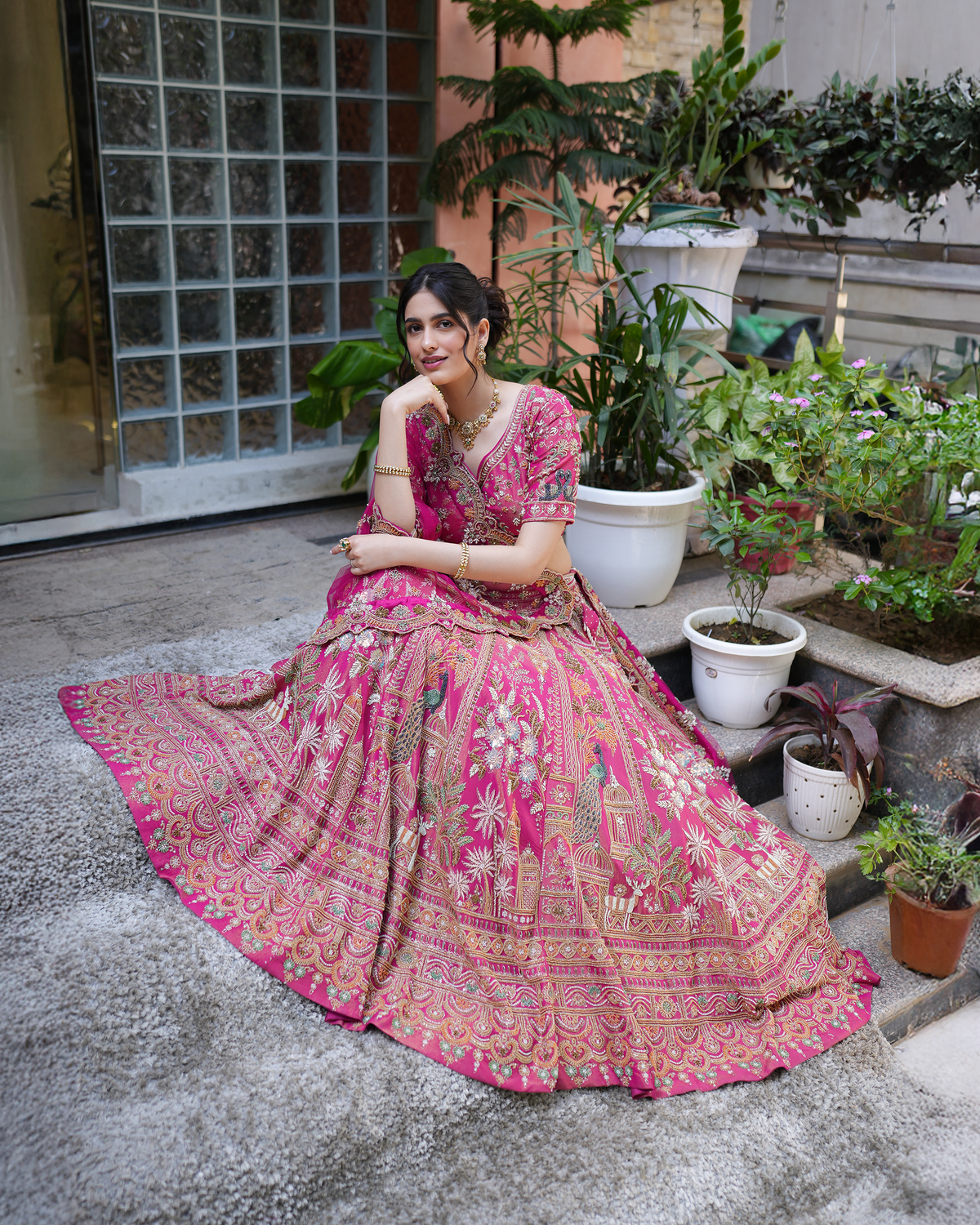 Aakriti by House of Somarra — Seated full-length view of the fuchsia lehenga spread across the steps.