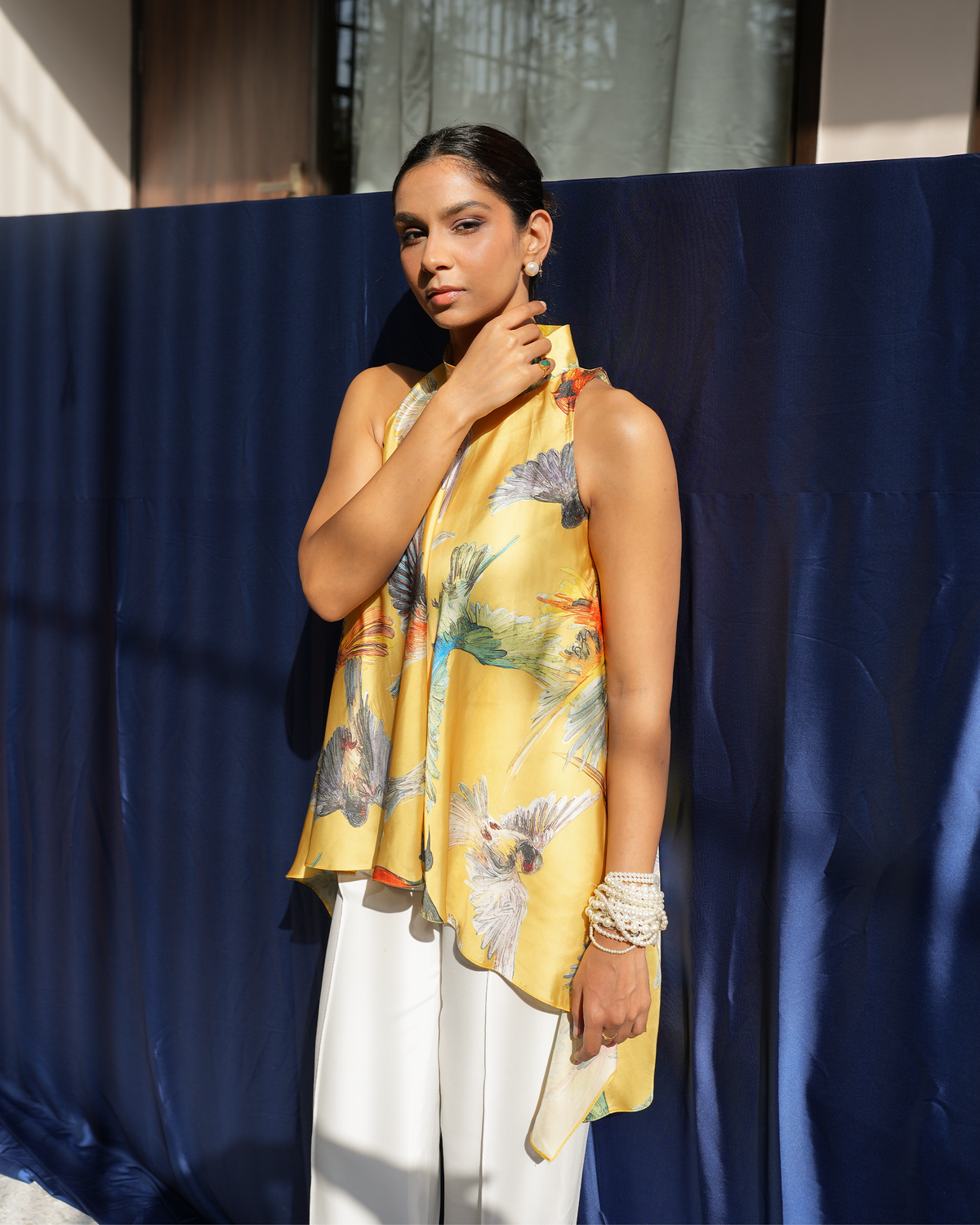 Jiya by House of Somarra — Three-quarter view of the asymmetric halter top and white trousers.