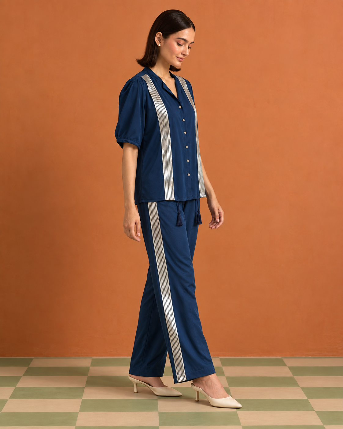 Tarini by House of Somarra — Walking side view showing the blue trousers' metallic stripe.