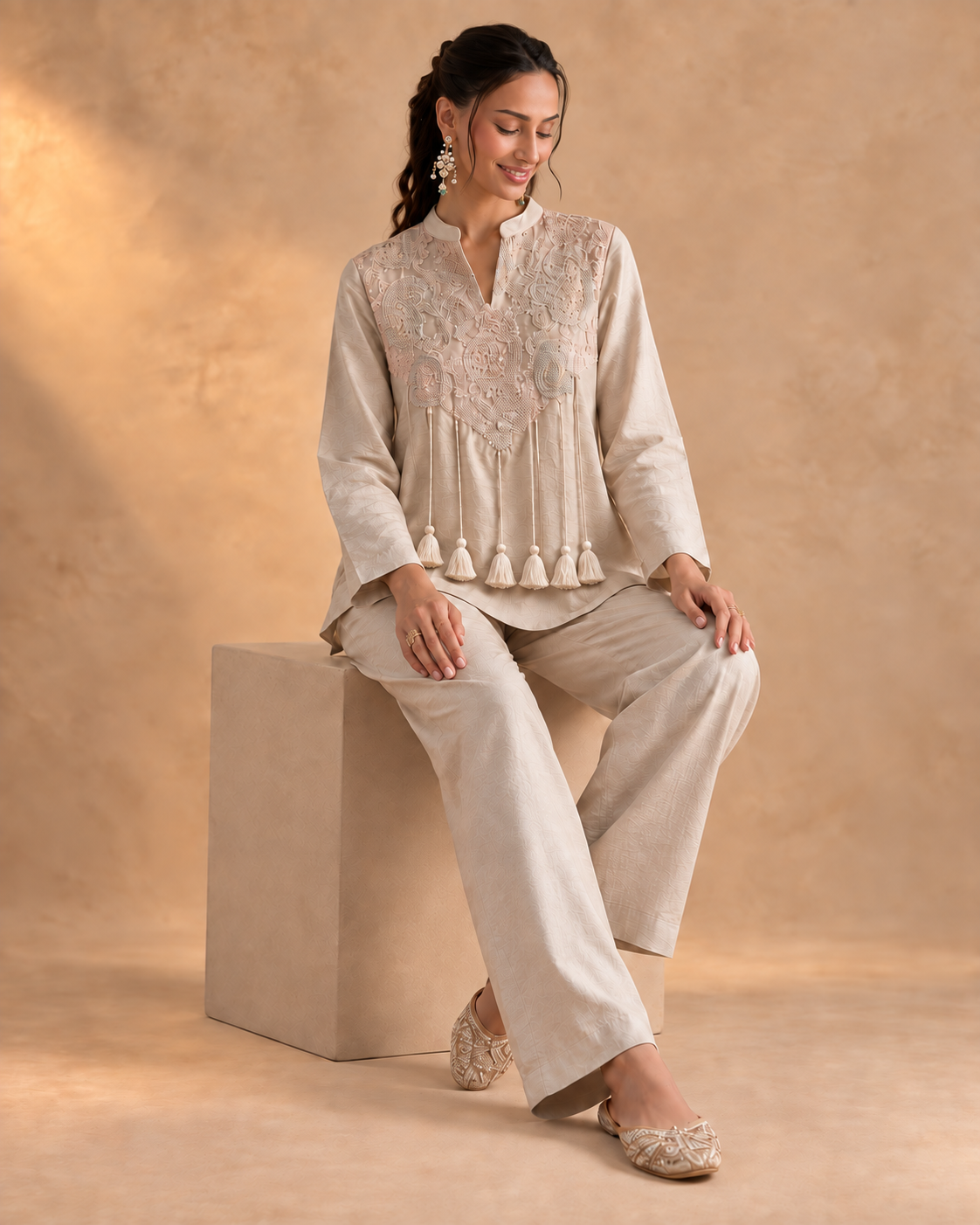 Noorika by House of Somarra — Seated view showing the pale blush ensemble and tassel details.