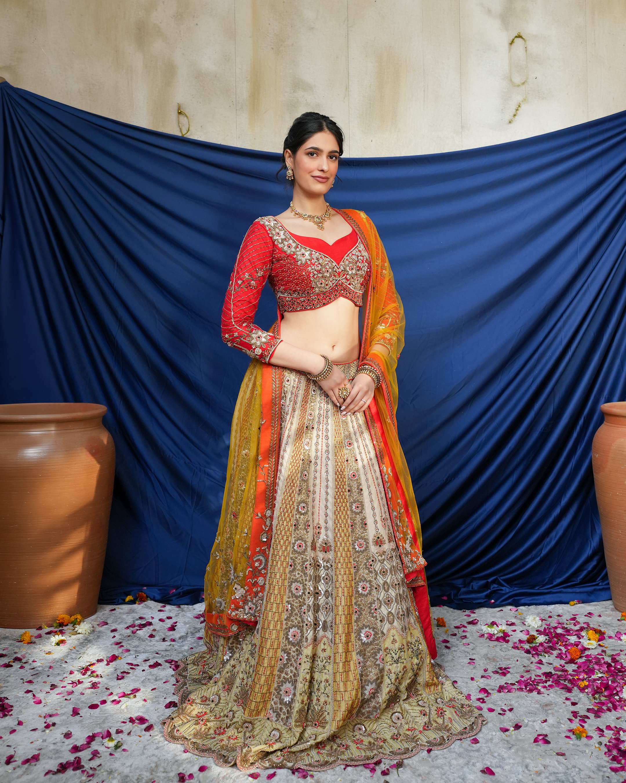 Amira by House of Somarra — Front view of the gold-toned bridal lehenga, red blouse and orange dupatta.