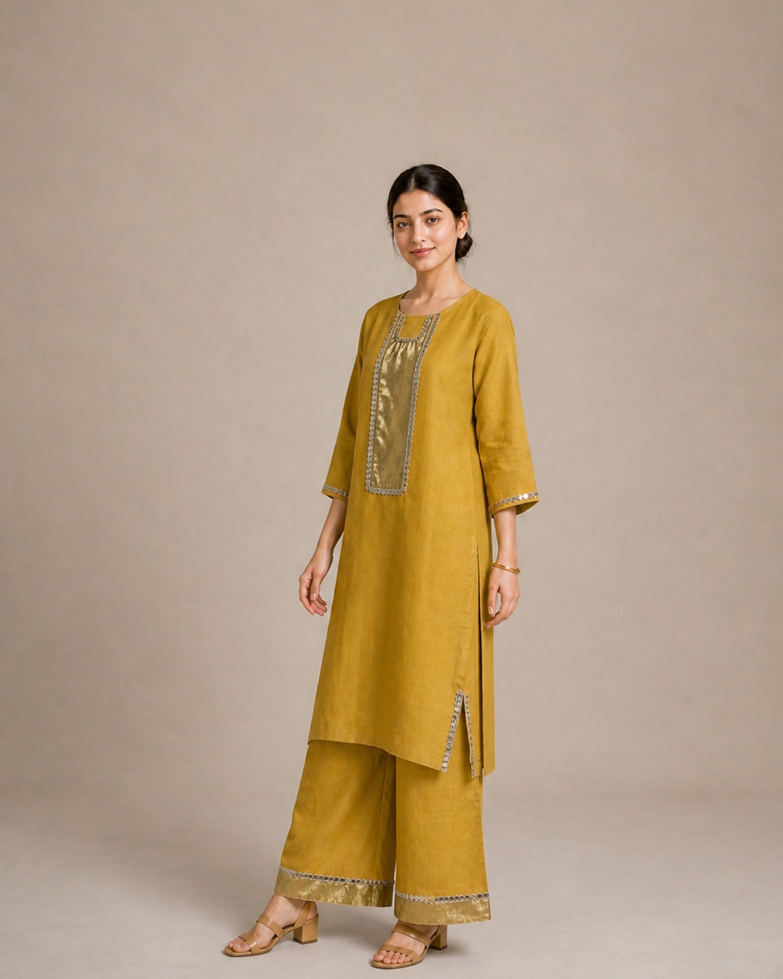 Three-quarter view of the Aabha gold-mustard linen co-ord showing the long sleeve and mirror-lace-finished side slit.
