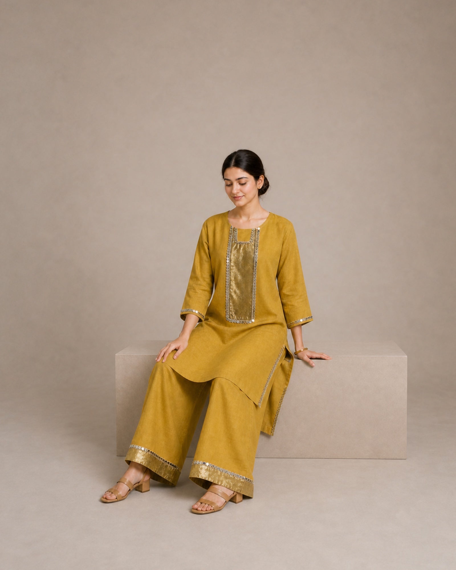 Aabha gold-mustard linen co-ord showing the palazzo and its antique-shimmer and mirror-lace hem finish.