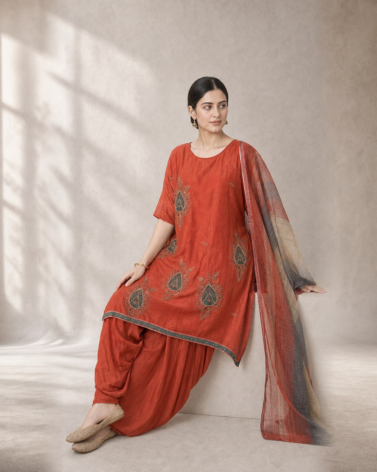 Agnira: Burnt Orange Embroidered Kaftan Dhoti Suit – seated three-quarter