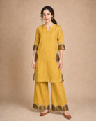 Front view of the Arpita golden-mustard pure-linen shirt-and-palazzo co-ord suit with antique-shimmer and mirror-lace semicircle patch work
