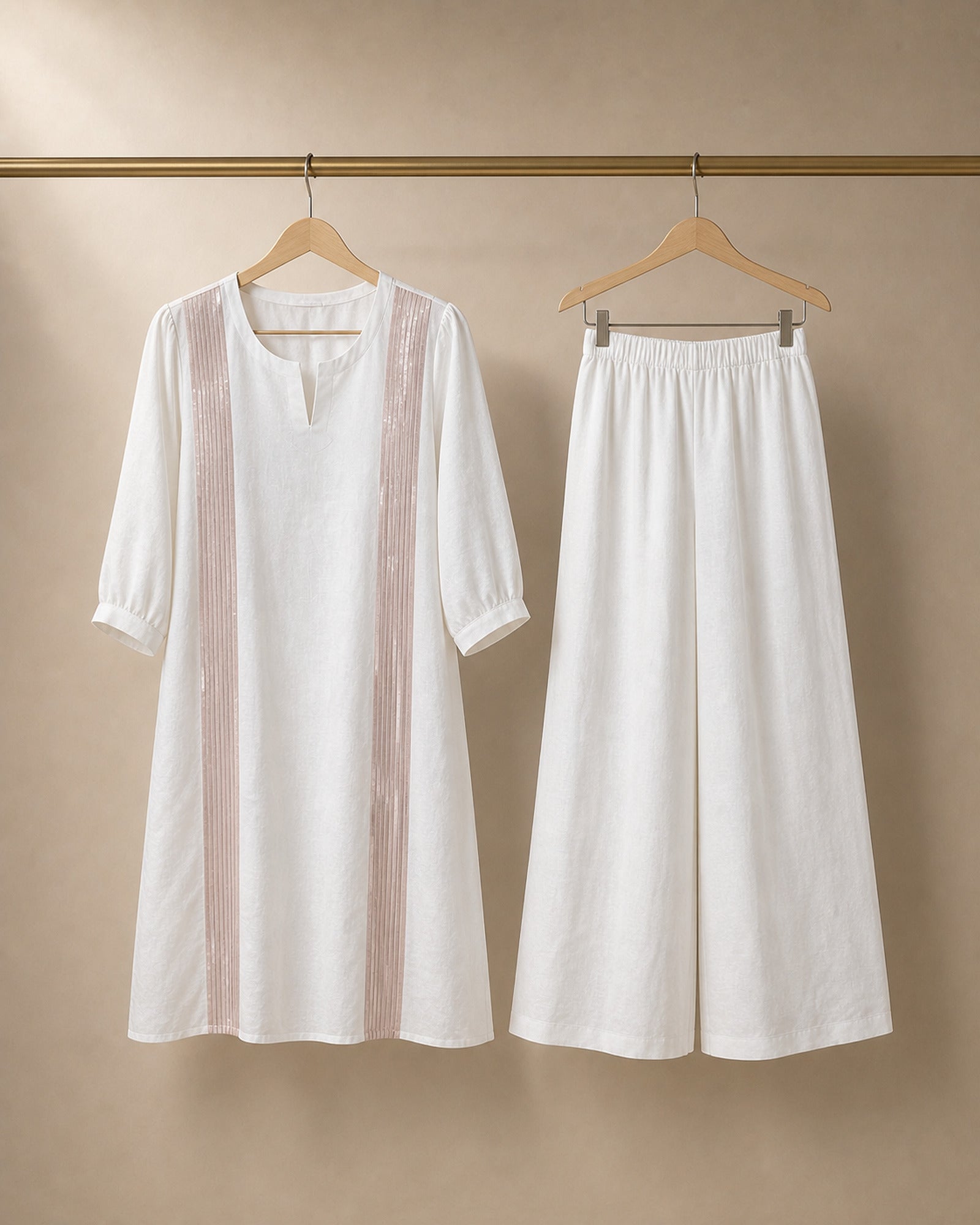 Hanger packshot of the Aurelle white linen co-ord top and matching broad linen palazzos with rose-gold-colour front trim