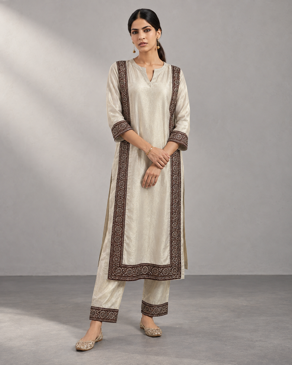 Roshni by House of Somarra — Front view of the ivory kurta and trousers with dark decorative borders.