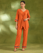 Arunika by House of Somarra — Front view of the bright orange draped top and straight trousers.