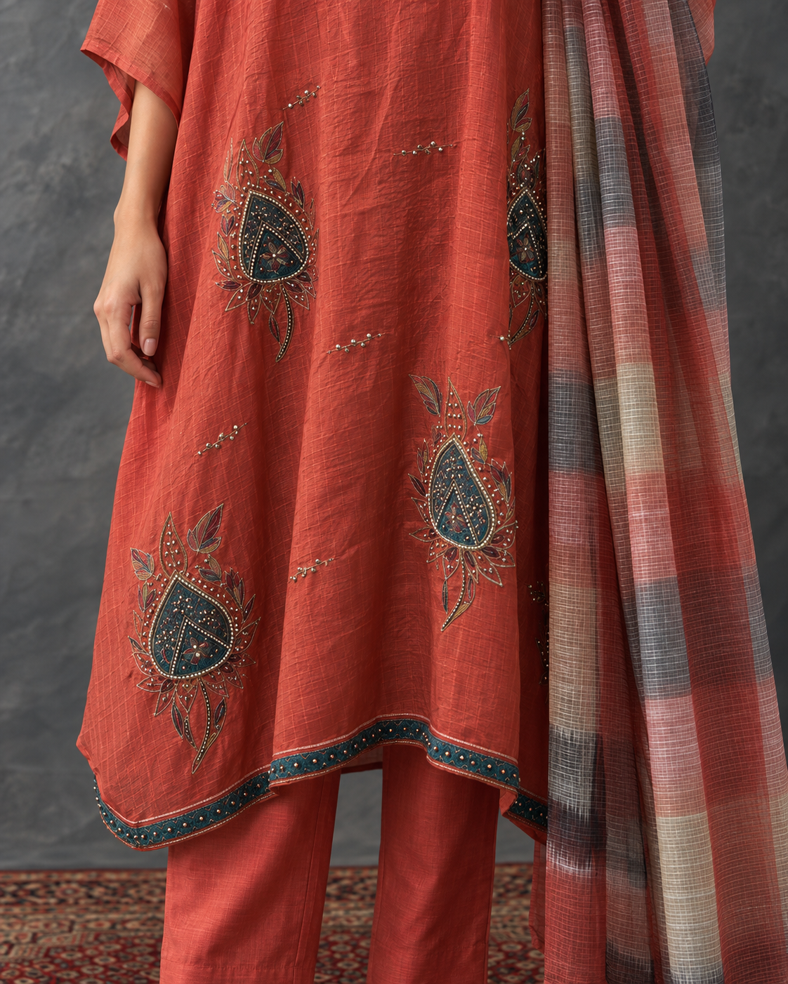 Agnira by House of Somarra — Close-up of the embroidered orange fabric and checked dupatta.