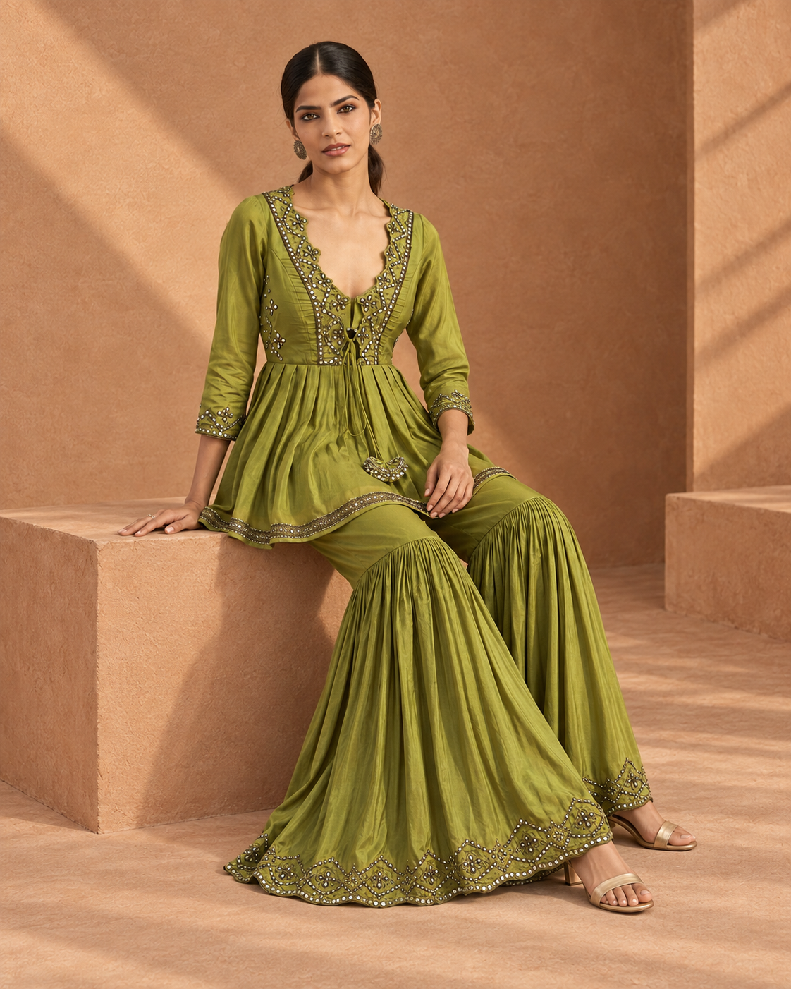 Madhavi by House of Somarra — Seated view showing the wide green garara and embellished borders.
