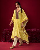 Amara by House of Somarra — Walking view showing the asymmetric yellow hem and loose silhouette.
