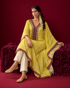 Amara by House of Somarra — Seated view showing the yellow kaftan drape and ivory trousers.