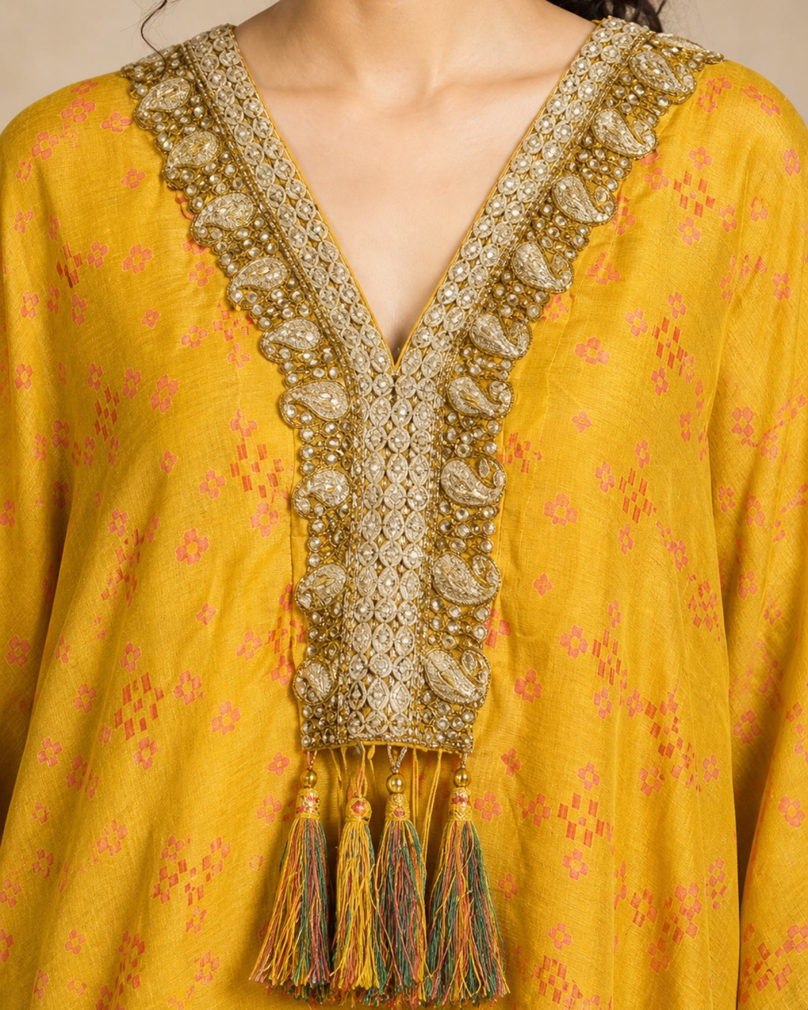 Close-up of the Sunehri kaftan front yoke with hand-embroidered zari and stone border and tassel bunch