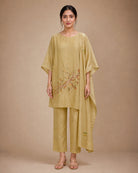 Front view of the Taru solder-beige Chanderi-material co-ord suit with a wide round neckline, draped sleeves, lower-front branch-and-leaf appliqué, narrow bottom and stole