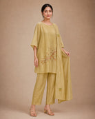 Three-quarter view of the Taru solder-beige Chanderi-material co-ord suit, showing the draped upper, narrow bottom and stole