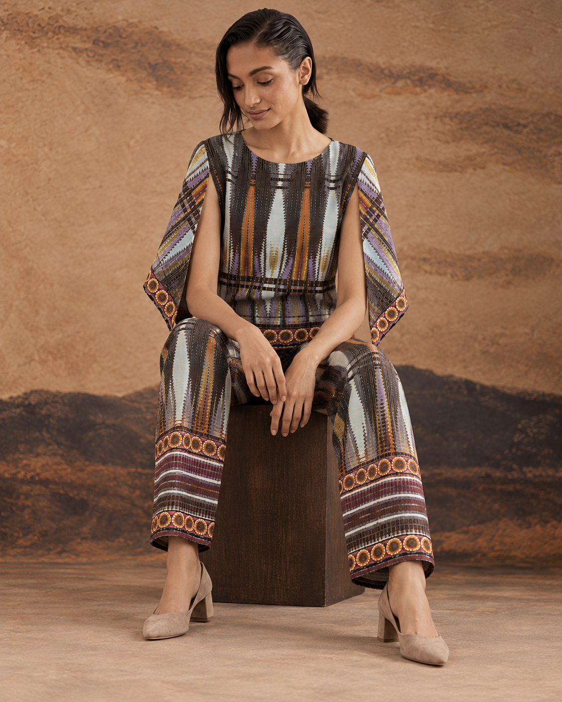 Aroha by House of Somarra — Seated view showing the patterned trousers and loose top.
