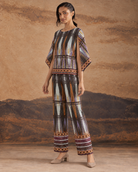 Aroha by House of Somarra — Side view of the multicoloured geometric top and matching wide trousers.