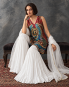 Meenal by House of Somarra — Seated view showing the white flared pants beneath the printed top.