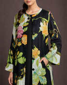 Close-up of the Vanika botanical-print modal-satin dress, showing the round neckline, black front buttons, side pocket and black inner